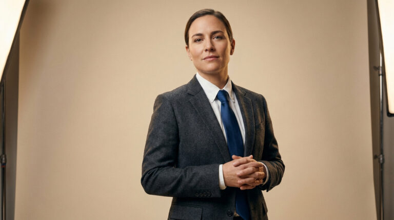 Portrait d'une femme d'affaires en blazer, mains jointes, sur fond neutre